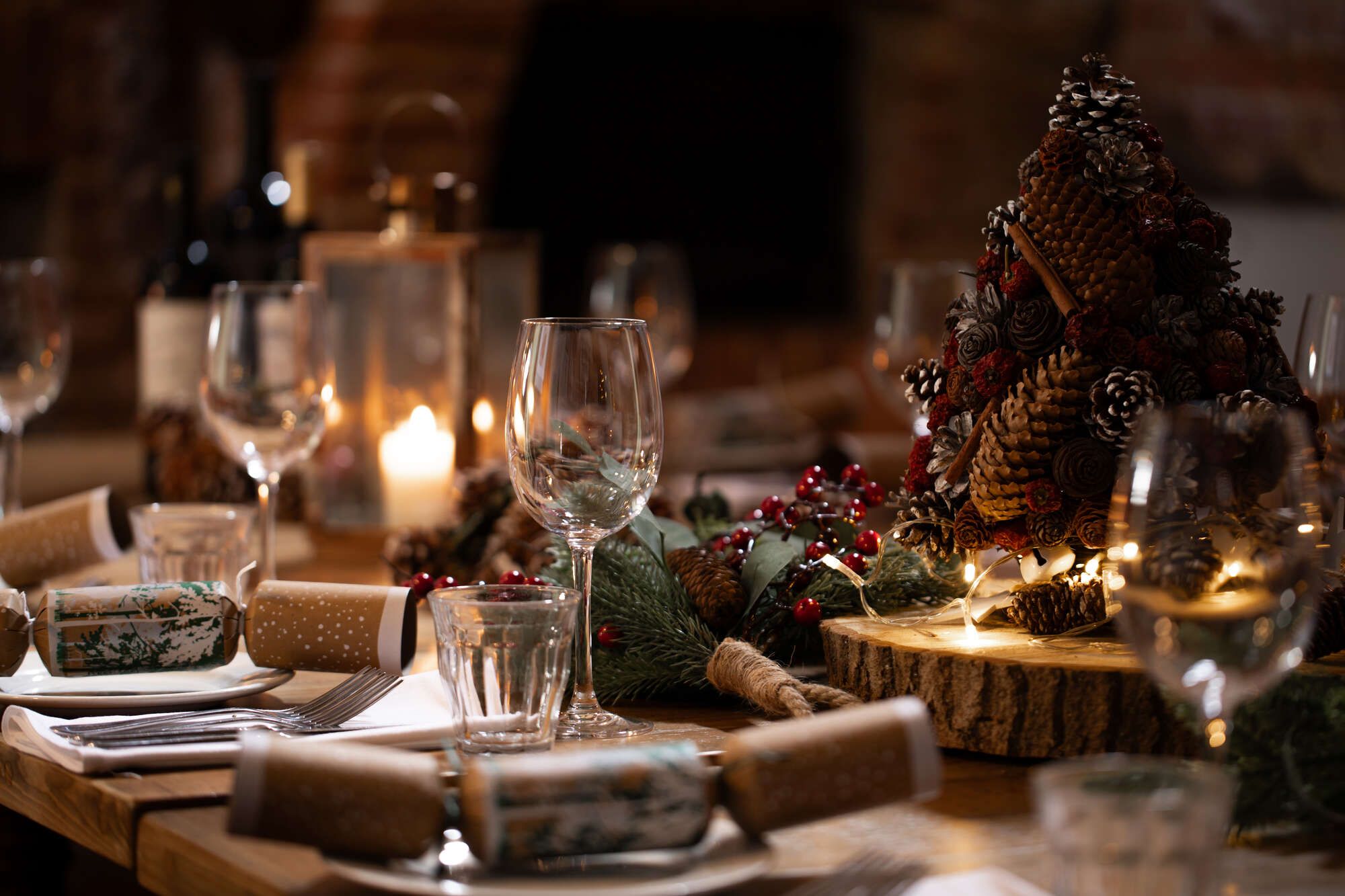 Christmas table set with candles, crackers, white tabke cloth and linen napkins